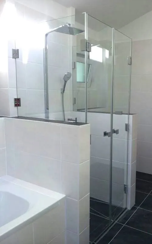 Glass shower on a wall ledge next to the bath
