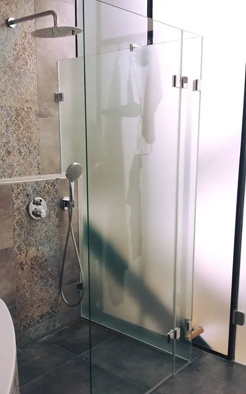 Glass shower in frosted glass in front of patterned tiles