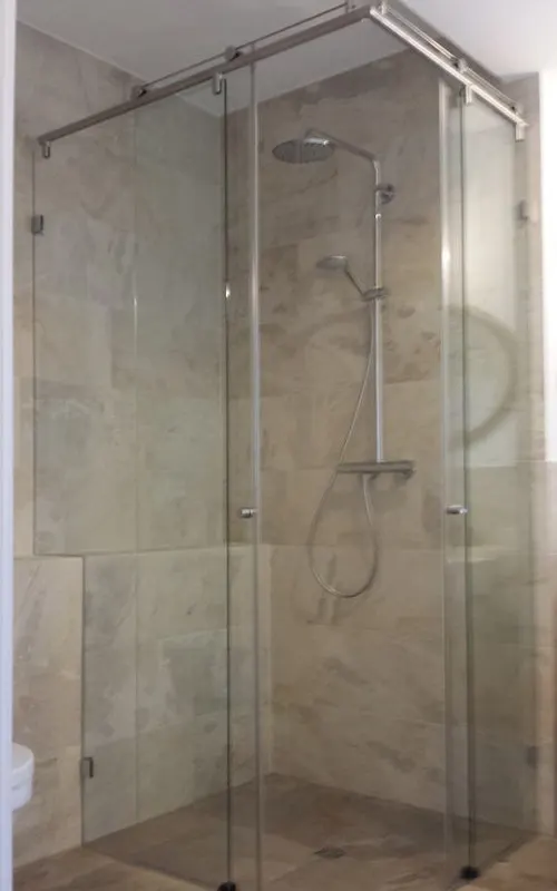 Clear-glass corner shower with sliding doors on a track