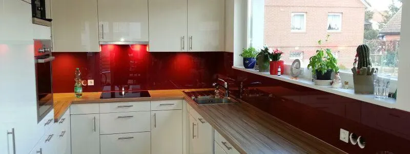 Kitchen splashback in red lacquered glass above a white kitchen